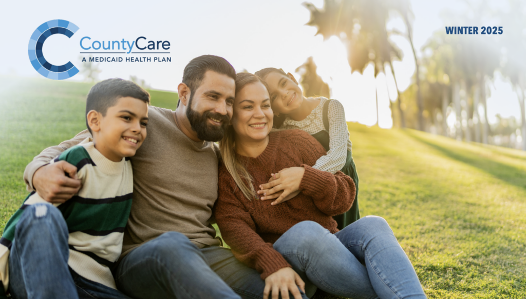 A smiling family of four sits closely together on grass in a sunlit park. The CountyCare Medicaid Health Plan logo and “Winter 2025” appear in the image corners.